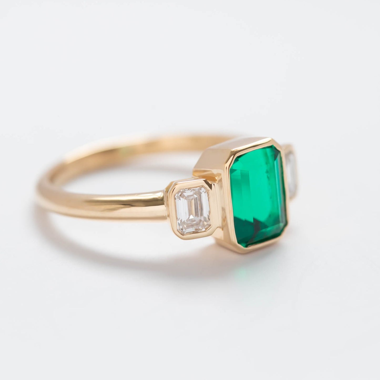 three stone ring with lab emerald in yellow gold