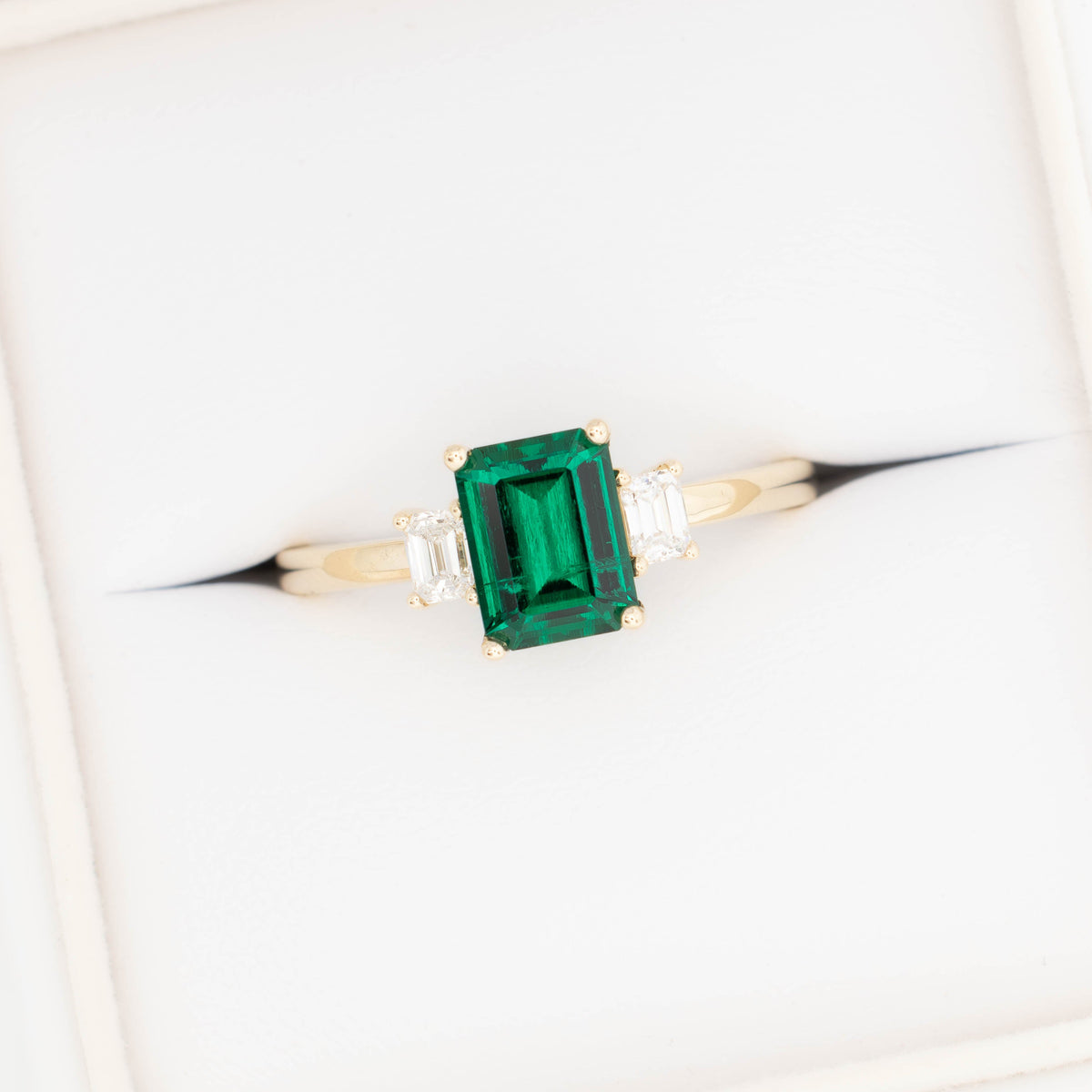 ami three stone ring in yellow gold with step cut lab emerald