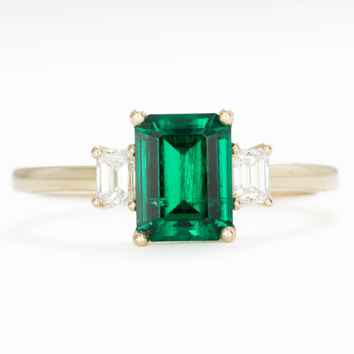 ami three stone ring in yellow gold with step cut lab emerald