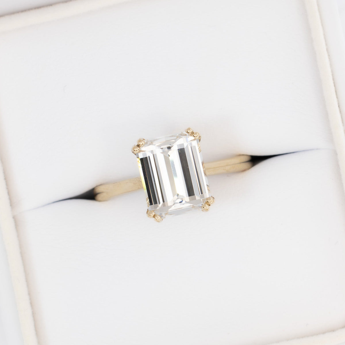 bailey solitaire ring in yellow gold with step cut white lab sapphire