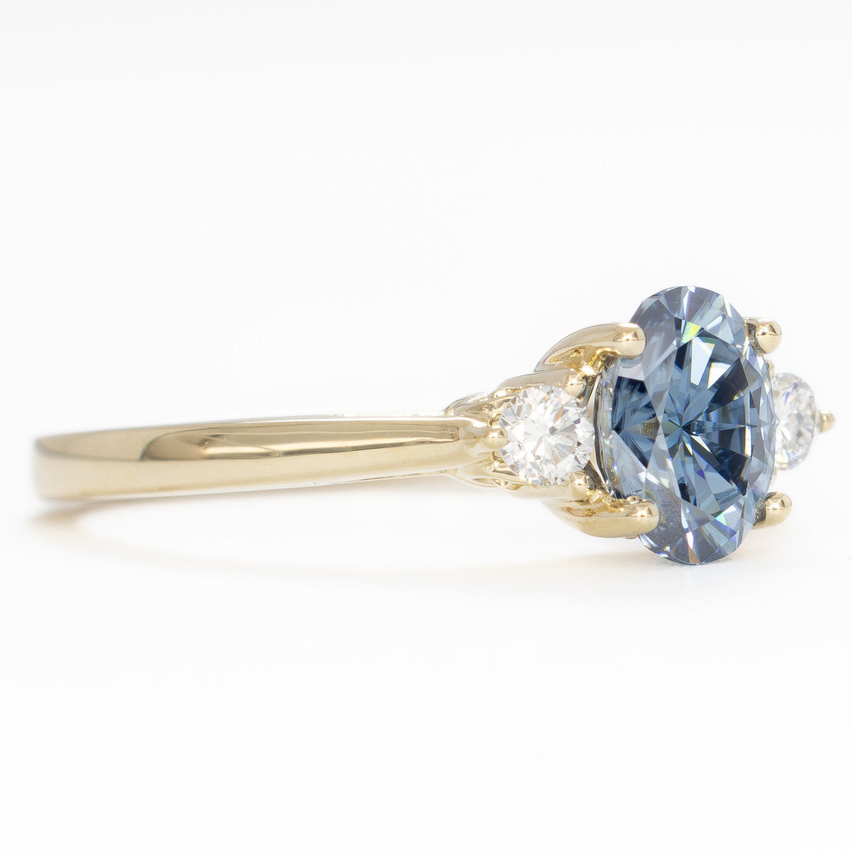 carina three stone ring in yellow gold with oval blue moissanite