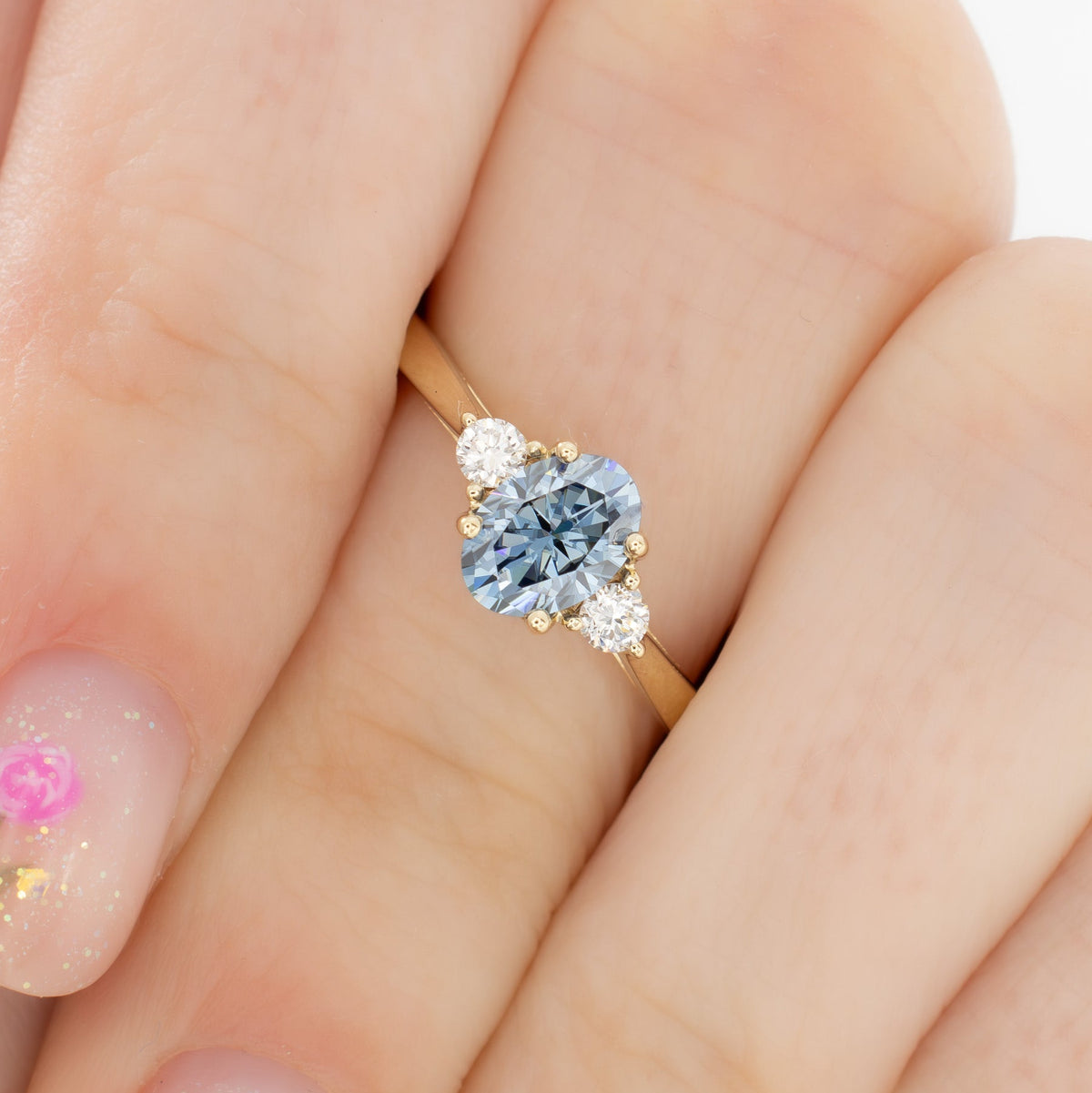 carina three stone ring in yellow gold with oval blue moissanite