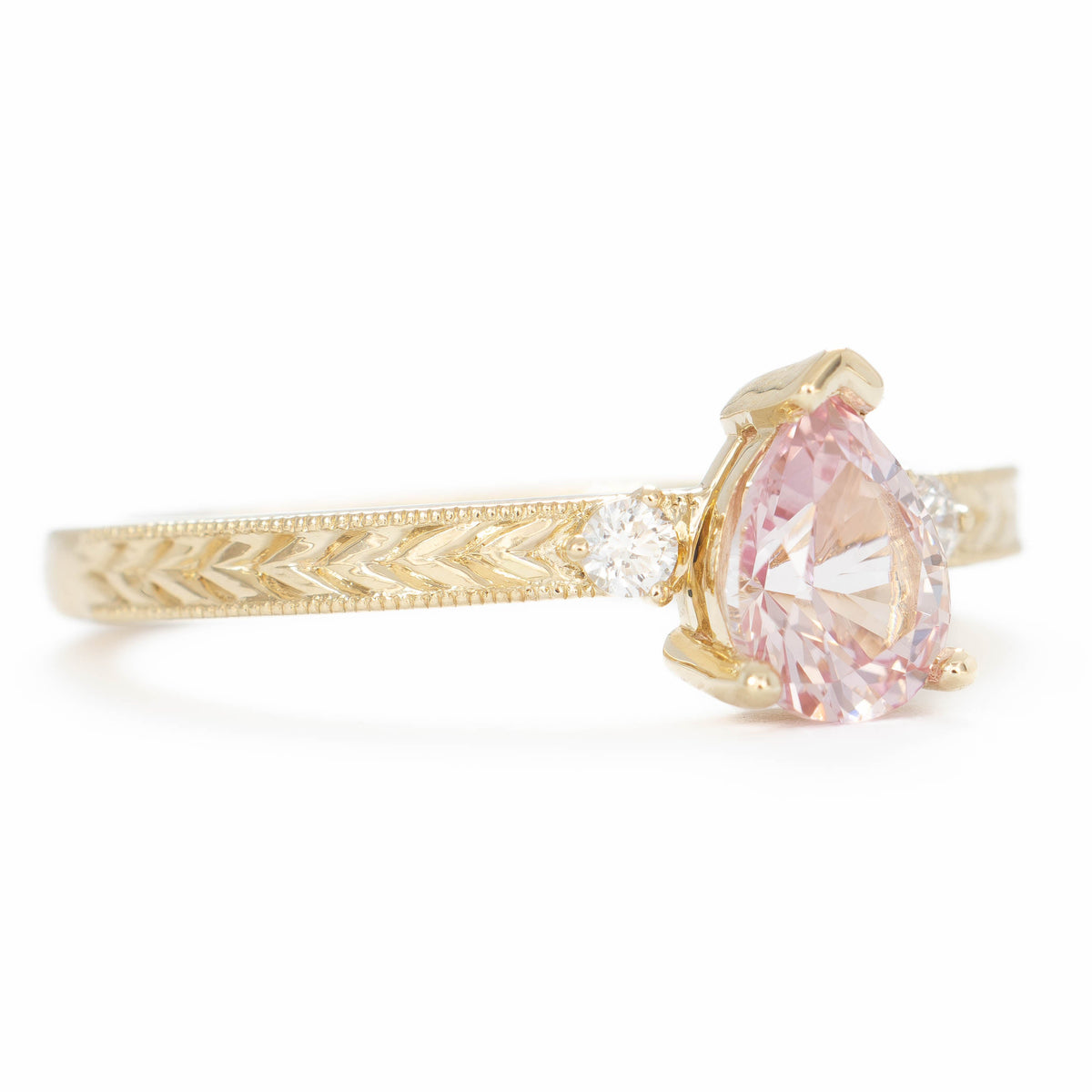 meera three stone ring with chevron detail in yellow gold and pink lab sapphire pear