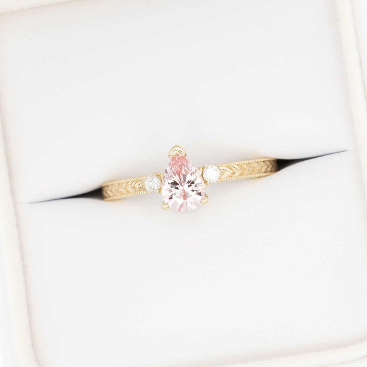 meera three stone ring with chevron detail in yellow gold and pink lab sapphire pear